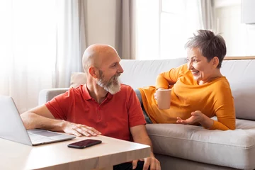 Gordijnen Portrait Of Happy Senior Spouses Chatting And Drinking Coffee At Home © Prostock-studio
