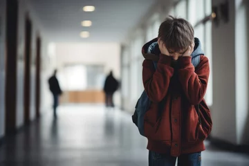 Foto op Plexiglas Upset boy covered his face with hands standing alone in school corridor. Learning difficulties, emotions, bullying in school © vejaa