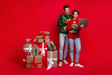 Zelfklevend Fotobehang Full body portrait of positive partners use netbook pile stack delivery x-mas giftbox order isolated on red color background © deagreez