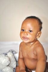  African Baby Toddler Smiling Sitting On Bed Indoor