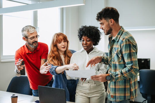 Diverse colleagues discussing financial data report during a meeting in office - Powered by Adobe