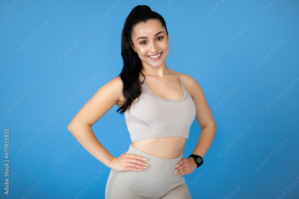 Wall mural Attractive young sporty lady posing on blue background