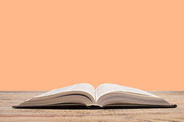 open book. Composition with hardback books, fanned pages on wooden deck table and orange background. Books stacking. Back to school. Copy Space. Education background.