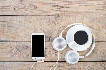 Headphones, mobile phone, idiobook, coffee cup on a wooden table. The concept of leisure and learning, hobby. Listen to music, literature. Top view with copy space.