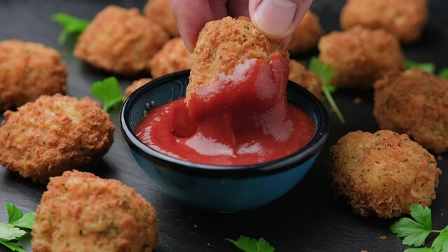 Dipping Potato croquettes with ham and cheese in ketchup