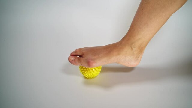Massage a woman's foot with a yellow ball for hallux valgus.