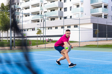 man playing pickleball game, hitting pickleball ball with paddle, outdoor sport leisure activity.