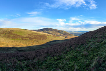 Panorama of rolling hills of the Scottish Highlands in colourful autumn with trail and expansive views in warm soft light