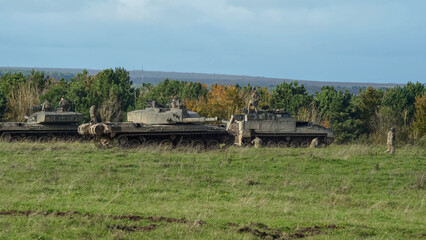 four British army FV4034 Challenger 2 ii main battle tanks and a REME Warrior FV512 in a grass...