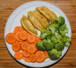 potatoes, bocoi and carrots cut on a plate