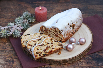 Christmas stollen cut into pieces on a wooden board. Traditional German cake for Christmas with raisins and powdered sugar