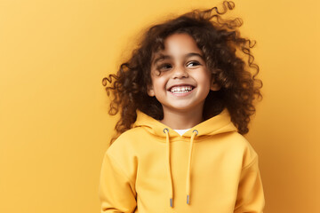 Obraz na płótnie Canvas Portrait of a happy smiling curly child girl on yellow background