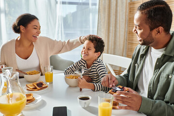 happy modern african american family in casual homewear having fun together at breakfast table