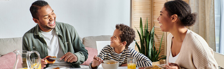 cheerful modern african american family having their breakfast and smiling at each other, banner - obrazy, fototapety, plakaty