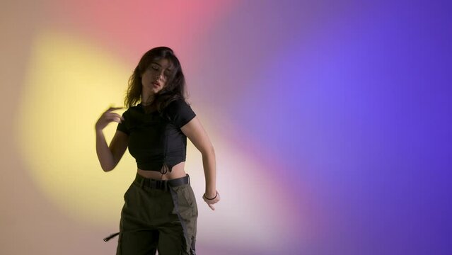 Attractive woman dancing in studio energetic jazz funk dance, close up shot isolated on soft colorful light background.