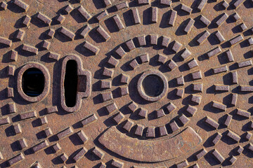Ivry-Sur-Seine, France - 09 30 2021: view of a rusty brown manhole cover under bright light.