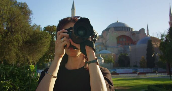Woman traveler taking pictures on camera in front of Ayasofya or Hagia Sophia Mosque, female blogger taking pictures