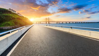 Zelfklevend Fotobehang asphalt highway road and bridge at sunset by the sea © Emanuel