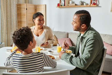 Fototapeta na wymiar happy african american family in casual attires smiling lovingly at each other during breakfast