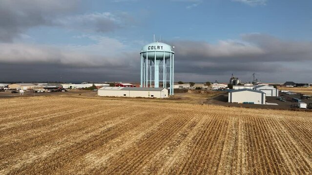 Flying over cut field towards water tower in Colby, Kansas viewing the town sprawled out behind.