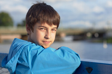 A caucasian boy in a blue jacket on the street