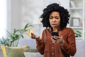 Upset unhappy and cheated woman sitting at home on sofa in living room, displeased rejected online money transfer error, holding bank credit card and phone - Powered by Adobe