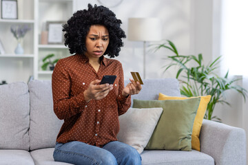 Upset unhappy and cheated woman sitting at home on sofa in living room, displeased rejected online...