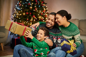 joyous loving african american family exchanging presents and hugging warmly on Christmas evening