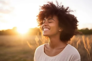 Fotobehang Backlit Portrait of calm happy smiling free black woman with closed eyes enjoys a beautiful moment life on the fields at sunset © Adriana