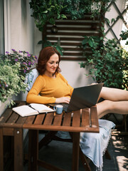 Portrait of a woman working at home terrace surrounded by her home plants.