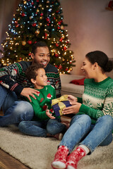 vertical shot of happy african american woman giving present to her son and husband, Christmas