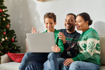 happy african american family spending time together while son waving at laptop camera, Christmas