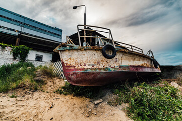 Old rusty fishing vessel on the coast. Rusty old abandoned iron fishing boat which is pulled out on...