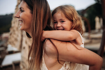 Cute young daughter on a piggy back ride with her mother.
