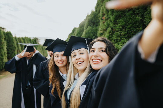 Happy college graduates, in gowns and caps, celebrating their milestones outdoors. They take photos, selfies, and create memories that will last a lifetime.