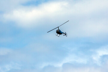 Fototapeta na wymiar helicopter crosses the blue sky with clouds. Transportation. Urban.