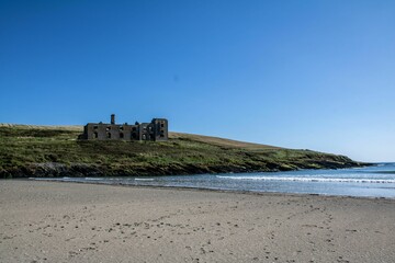 Ruins of Howe Strand Coast Guard Station in front of the blue sea in Ireland