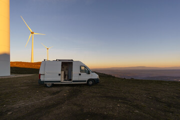 Wind turbines at Serra da Arada over mountain landscape at evening sunset with camper van on road trip, Sao Pedro do Sul, Portugal - obrazy, fototapety, plakaty