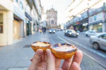 Tow Hand with Portugal's traditional sweet dessert Pastel de nata egg custard tart pastry with street in Porto, Portugal - obrazy, fototapety, plakaty