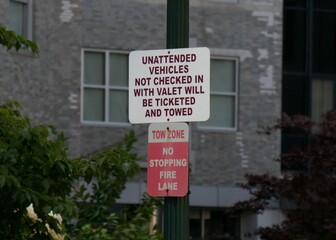 Closeup of a warning board on an iron pole with building blurred background