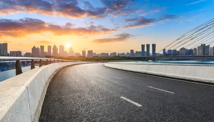 Poster asphalt road and bridge with city skyline at sunset © Art_me2541