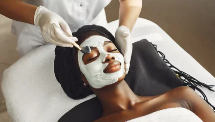 Photo sur Plexiglas Spa beautiful african woman getting face massage in beauty spa cosmetologist smears nutrient mask in beauty salon face peeling mask spa beauty treatment skincare selfcare concept