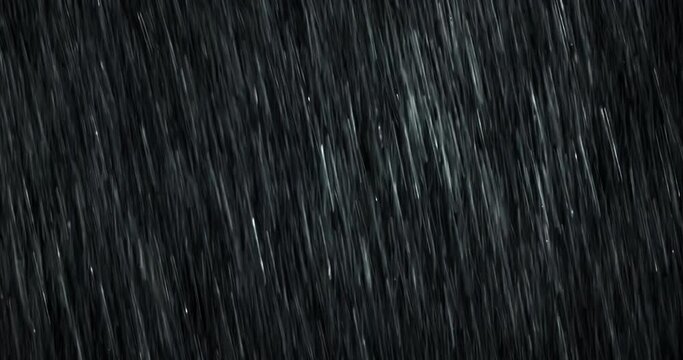 A heavy diagonal rain falls in front of the black screen in 4K loopable high-speed footage. Raindrops splashing. Rain closeup VFX insert. Practical, seamlessly loopable. Heavy rainstorm hitting black.