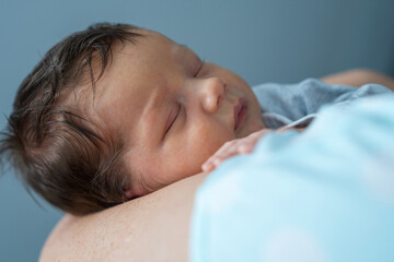 Mom holds a newborn boy, the baby sleeps sweetly. Mother's hands and baby close-up. Infant health...