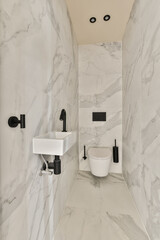 a bathroom with white marble walls and black fixtures on the wall, there is a toilet next to the sink