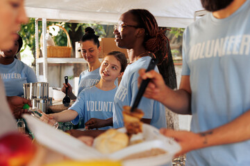 Image shows essence of support, giving, and volunteering as charity workers share warm meals and...