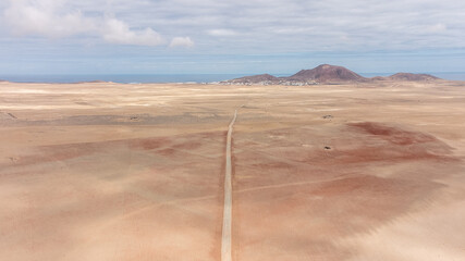Aereial drone view from above of a convertible car Driving on a rural dirt road in lanzarote,...