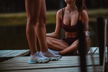 Partial shot of sexy girls resting on a bridge after training in the park.