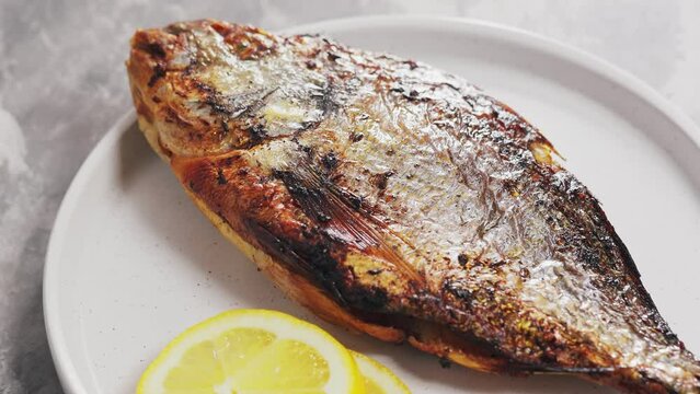 Fried Dorado with Lemon on White Plate. Panning Camera Shot