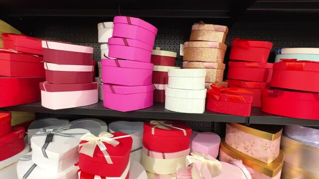 Many colorful heart-shaped gift boxes with bows to give to your loved one on Valentine's day, birthday, mother's day on the shelf in the store, all for decoration. Red and pink boxes tied with ribbons